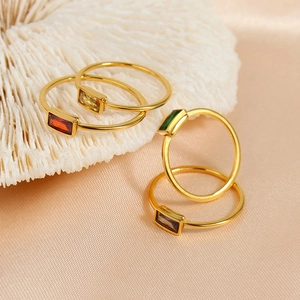 Elegante gouden titanium ringen met gekleurde zirkonia op wit koraal en satijnstof