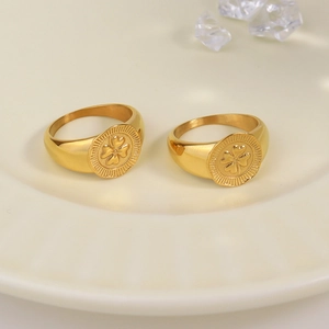 Golden stainless steel signet ring with engraved four-leaf clover on ceramic tray