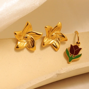 Golden flower studs and tulip pendant earrings set on a textured stone display pedestal