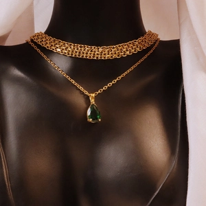 Gold layered necklace set featuring teardrop emerald zircon pendant on black mannequin
