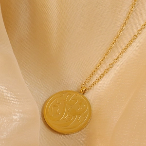 Gold stainless steel necklace with Arabic calligraphy circular pendant on silk fabric