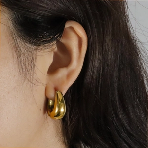 Boucles d'oreilles gouttes dorées polies au design géométrique sur l'oreille