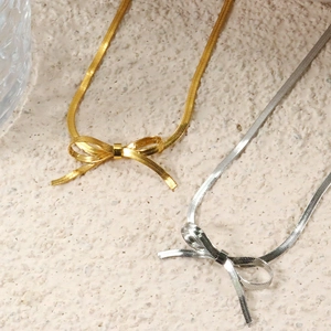 Vintage 18K Gold- und Silber-Bogenanhänger-Schlangenkette auf Steinoberfläche