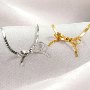 Elegante 18K Gold- und Silber-Schleifen-Halsketten auf weißem Seidenhintergrund