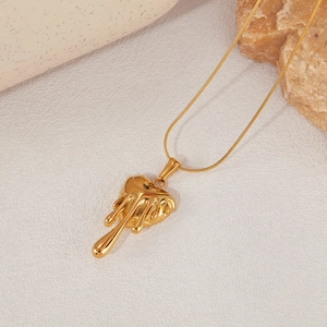 Détail macro du pendentif cœur en lave dorée montrant une texture fluide sur une chaîne serpent