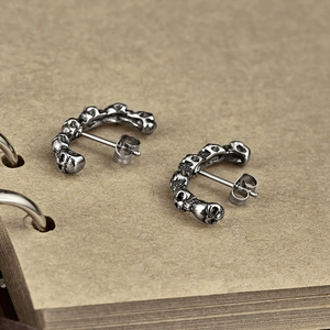 Vue détaillée de boucles d'oreilles tête de mort en acier sur fond de papier vintage