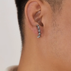 Détail d'une boucle d'oreille rétro en acier inoxydable avec crânes au style punk gothique