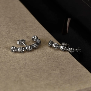 Détail de boucles d'oreilles tête de mort gothiques en acier inoxydable avec finition vintage