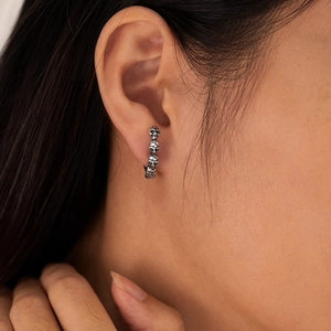 Gros plan d'une boucle d'oreille pour homme en acier inoxydable avec petits crânes