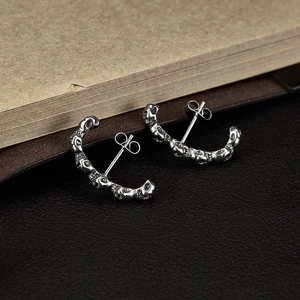 Détail des boucles d'oreilles créoles têtes de mort argentées au style gothique rétro