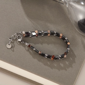 Dettaglio del bracciale da uomo con perline di ematite a V e pietre naturali su un libro