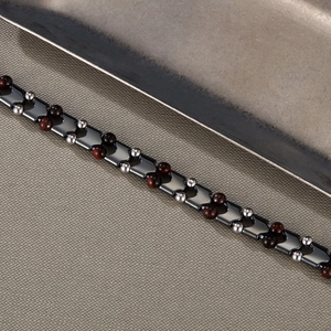Dettaglio del bracciale in acciaio inossidabile con perle di occhio di tigre rosso