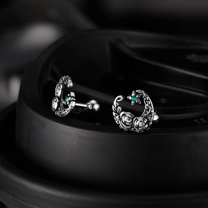 Macro shot of retro silver moon earrings with rose texture and green star zircon
