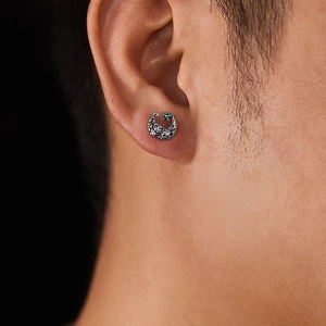 Detailed close-up of vintage steel rose earrings with green gemstone on the ear