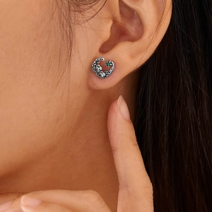 Close-up of vintage steel rose earrings with crescent moon and green gemstone inlay