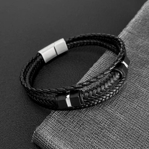 Detail of multi-layer black braided leather bracelet with silver magnetic buckle and beads
