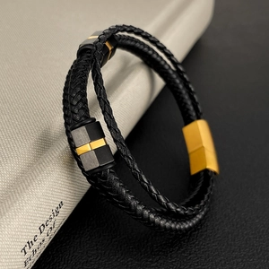 Close-up of black braided leather bracelet with gold magnetic clasp and metal accents
