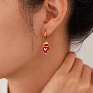 Boucles d'oreilles gants de Noël rouges avec crochets dorés portées par un mannequin