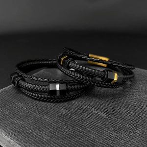 Close-up of braided black leather men's bracelets with stainless steel geometric beads