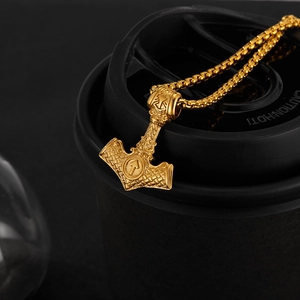Gros plan du pendentif Mjölnir viking doré avec nœuds celtiques sur une chaîne en acier