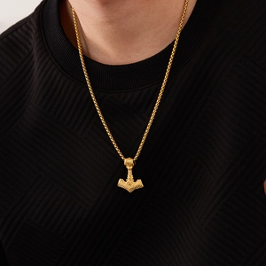 Détail du pendentif marteau de Thor doré avec des motifs de nœuds nordiques tressés