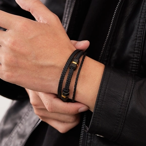 Detail of multi-layer braided leather bracelet with black and gold hexagonal metal charms