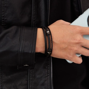 Detail of woven black leather bracelet with stainless steel geometric clasps on wrist