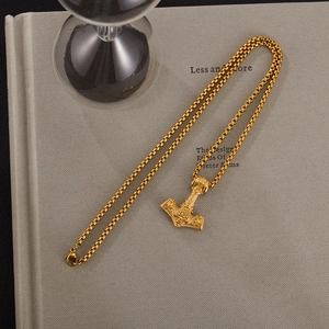 Gros plan du pendentif Mjölnir doré avec des gravures nordiques vintage complexes
