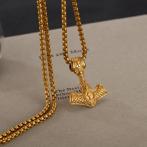 Vue macro du pendentif Marteau de Thor doré avec runes vikings et chaîne maille vénitienne