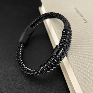 Macro detail of men's black braided leather bracelet with matte magnetic clasp on book