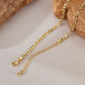 Macro-detail van een gouden Figaro-ketting met karabijnsluiting en druppelvormige hanger