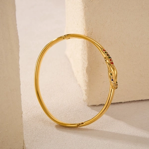 Dettaglio di un bracciale a nodo dorato con gemme colorate su pietra strutturata