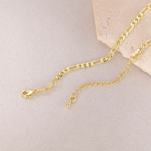 Detailed macro view of golden Figaro chain with lobster clasp and adjustable extension link