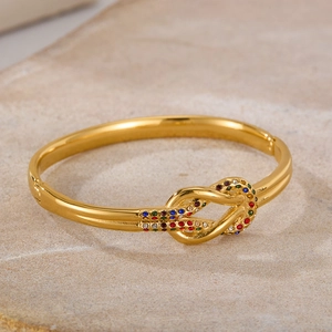 Dettaglio ravvicinato di un bracciale a nodo dorato con zirconi multicolore incastonati