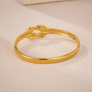 Vista macro del bracciale dorato con nodo e raffinati dettagli di diamanti pavé