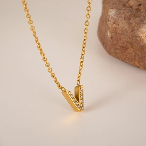 Macro detail of 18K gold letter V pendant necklace with micro-pave white crystal stones