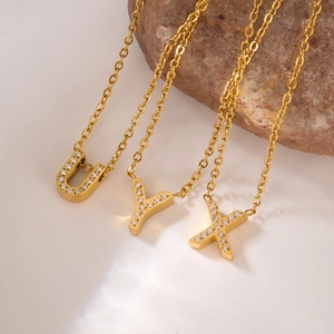 Macro detail of gold-plated U, Y, and X letter pendants with pavé-set zircon crystals