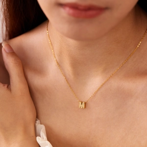 Detail shot of a gold-plated letter M pendant necklace with sparkling cubic zirconia stones