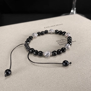 Primer plano de pulsera ajustable con cuentas negras facetadas y piedras de mapa