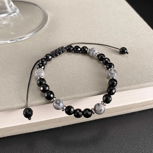 Detalle de pulsera ajustable de cuentas con ónix negro y piedra mapa en libro