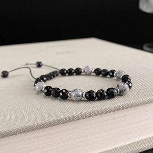 Pulsera ajustable de acero inoxidable con cuentas de ónix y mármol sobre un libro