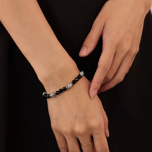 Primer plano de pulsera con cuentas de ónix negro y piedras de mármol en la muñeca