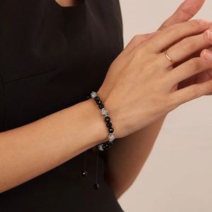 Detalle de pulsera ajustable de ónix negro y piedra mapa en la muñeca con cordón