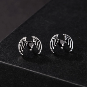 Macro detail of gothic bat wing stud earrings with black heart-shaped zircon stones