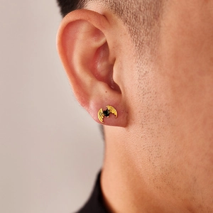 Close-up of heart-shaped black zircon earring with golden devil wing design on ear