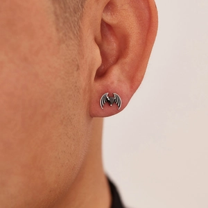 Close-up of gothic bat wing stud earring with black heart stone worn on male ear