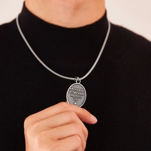 Detailed view of silver St. Michael Archangel pendant worn on a black knit sweater