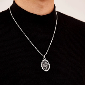 Close-up of Saint Michael silver pendant on box chain worn over black sweater background