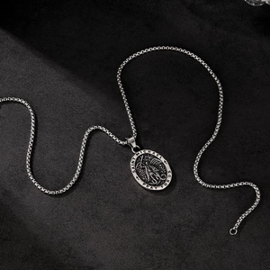 Detailed view of Saint Michael medallion pendant with box chain on a matte black surface