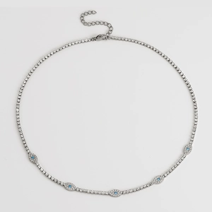 Detailed view of silver tennis necklace with evil eye charms and blue zircon stones